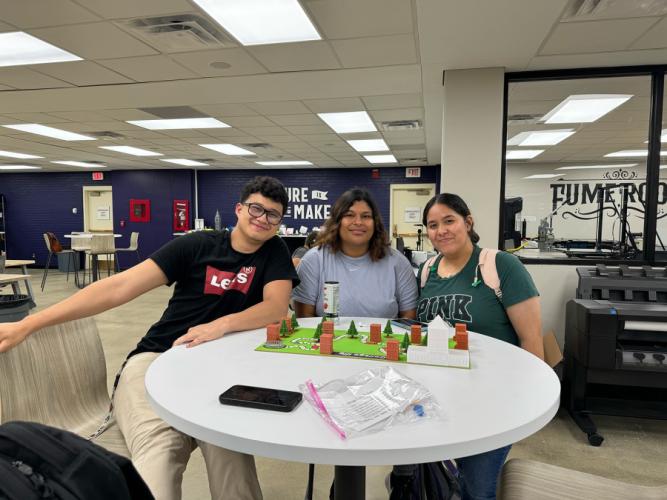three students in Dr. Dan Li's art appreciation class at SFA and the functional art in the form of board game they created