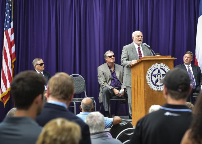 Seated on the stage are SFA President Dr. Baker Pattillo, Rep. Travis Clardy, and Dr. Adam Peck, SFA dean of Student Affairs. Chris Miller, Texas public policy manager for Uber, is seated behind the podium.