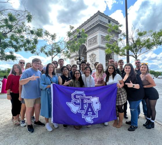 SFA College of Business students and faculty pose in front of the Arc de Triomphe