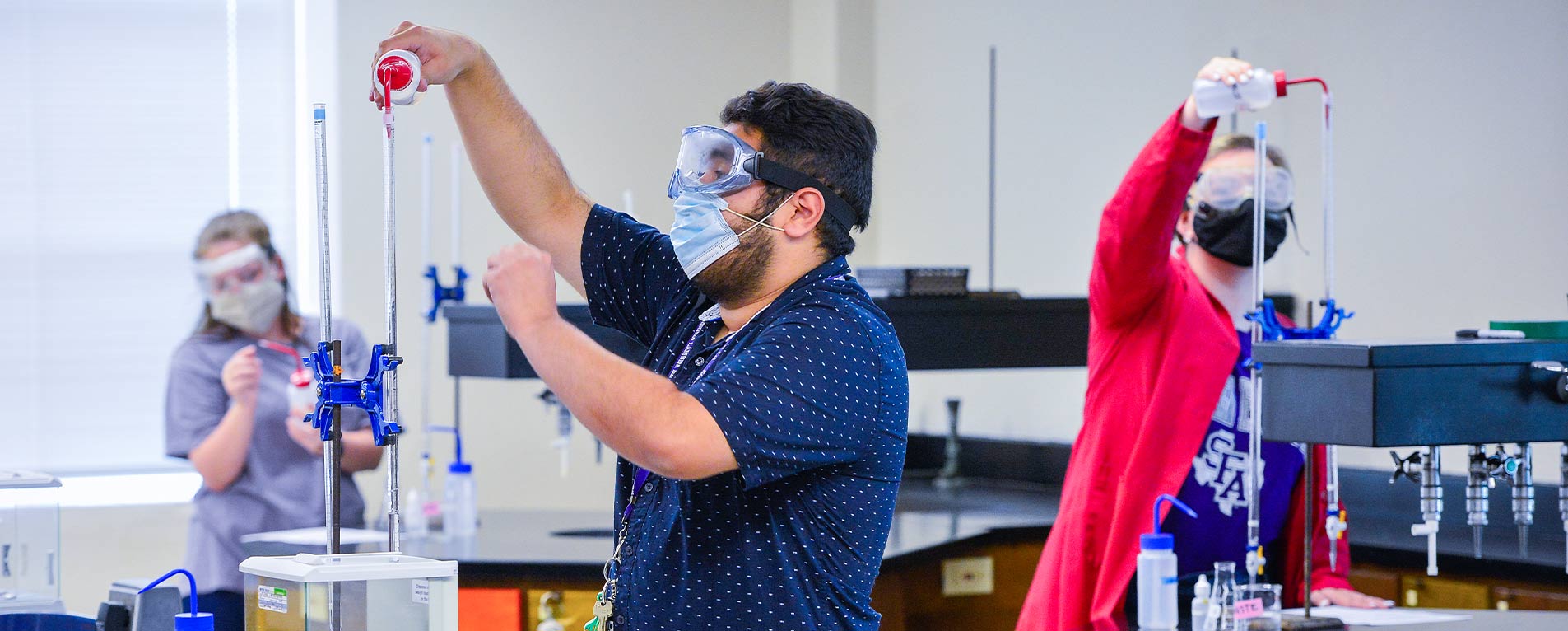 SFA graduate student Kaleth Salazar and Megan Carswell, senior mass communication student, titrate an acid with a strong base under the direction of Dr. Kefa Onchoke, professor of chemistry, while maintaining physical distancing protocols. Photo by Hardy Meredith