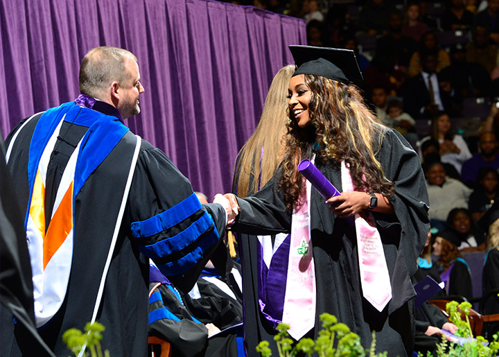 Student shaking hands with Dr. Gordon at commencement