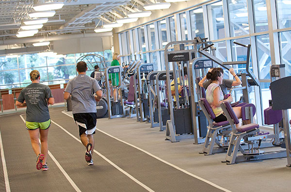two people running on indoor track inside campus recreation