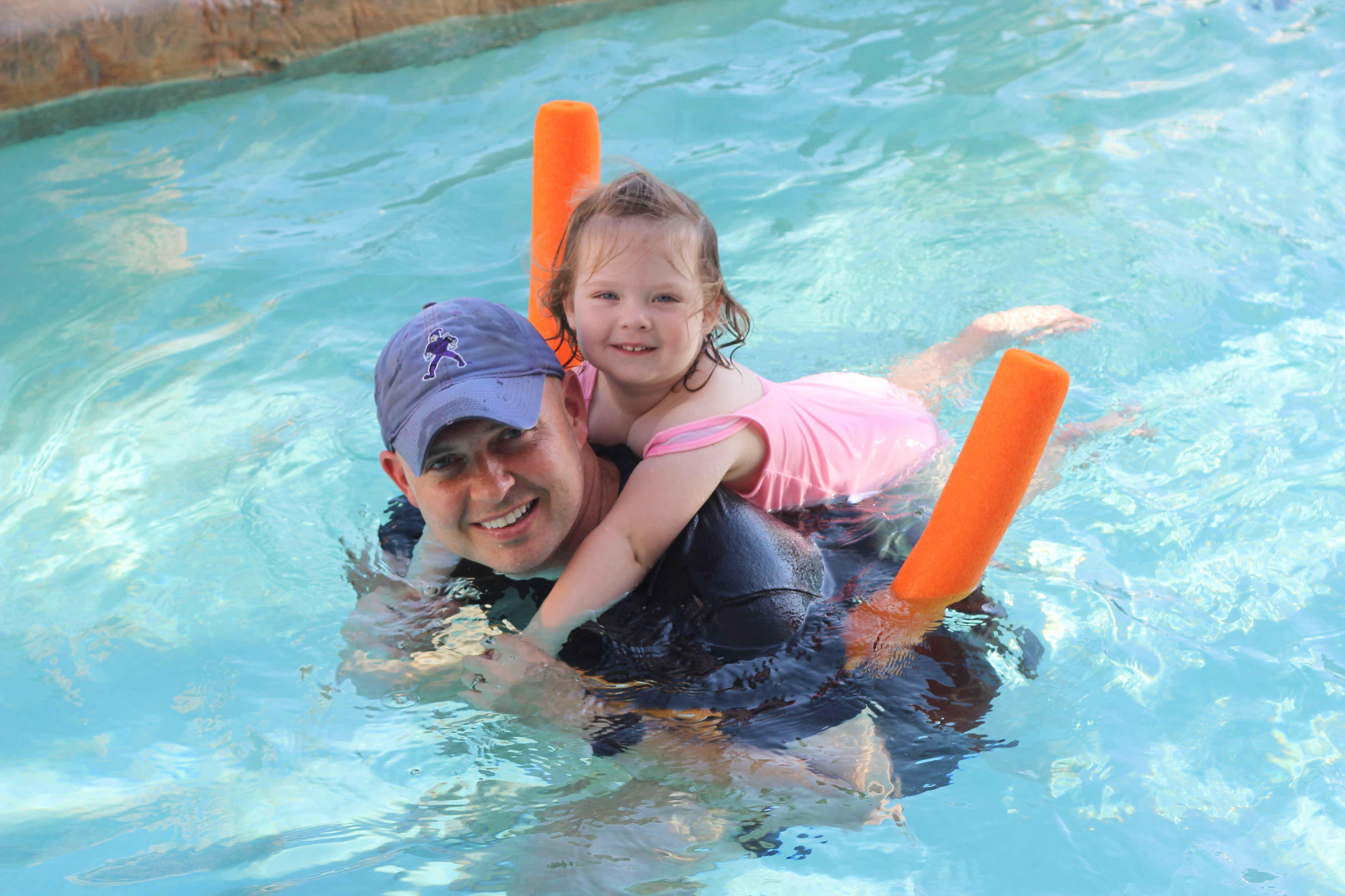 Parent and child smiling at the camera while enjoying the lazy river