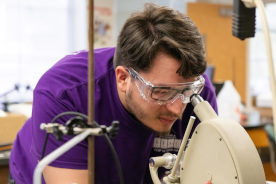 Student wearing safety goggles working with a laboratory instrument