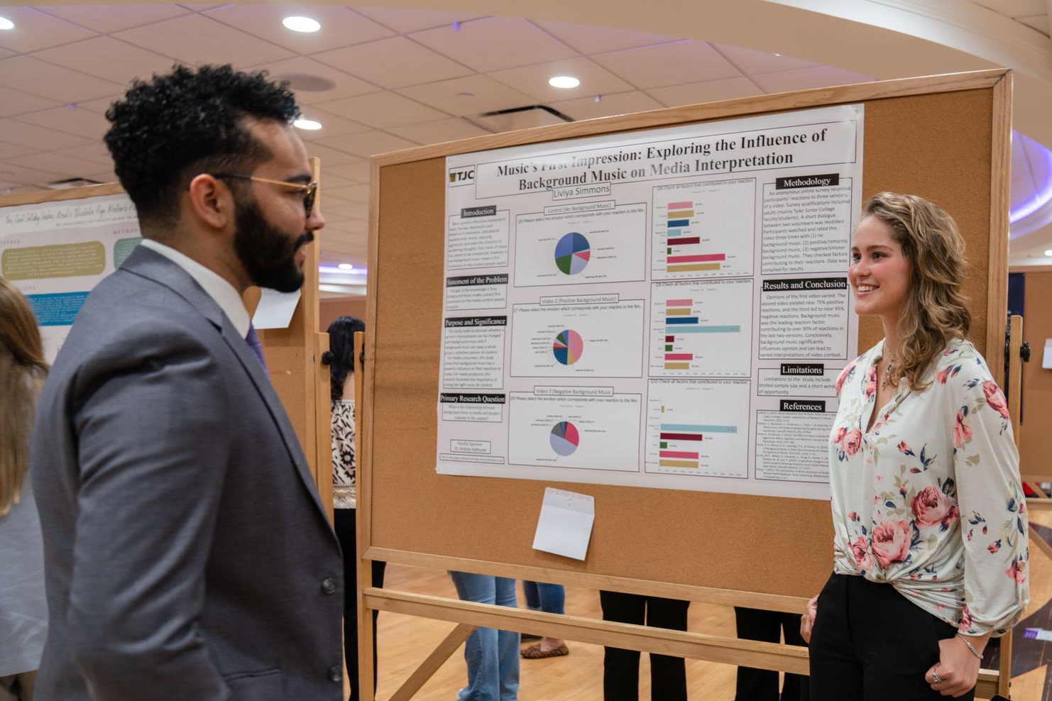 Student presenting research on a poster board to a conference attendee