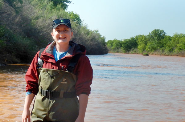 Student smiles while standing in water