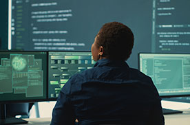 woman staring at multiple large computer screens