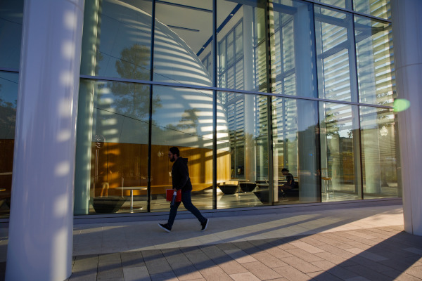 A student walks into the STEM building with the planetarium in the background