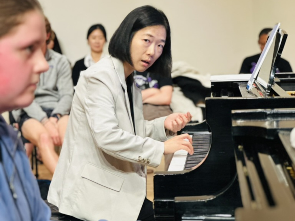 A faculty member and a student play a piano duet together