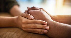 a woman's hands surrounding a man's clasped hands