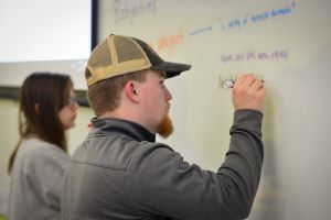 two students writing on a whiteboard
