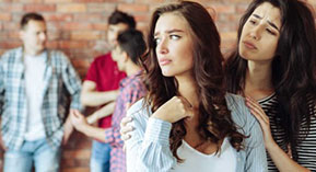 a young woman with a sad expression looking over her shoulder at a group of young men