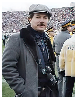 Still photographer Van Redin '75 stands on the Notre Dame Stadium sideline on the set of "Rudy" with his camera in tow. Redin credits "Rudy" as one of his favorite films to photograph.