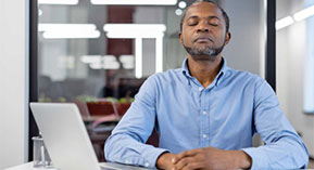 a man with his eyes closed, meditating at his desk