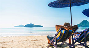 man relaxing in a chair under an umbrella at the beach