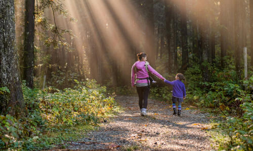 woman and girl walking on a trail in the woods