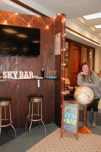 Jordyn Graham standing beside her design of an airport pop-up bar on display in the Steen Library.