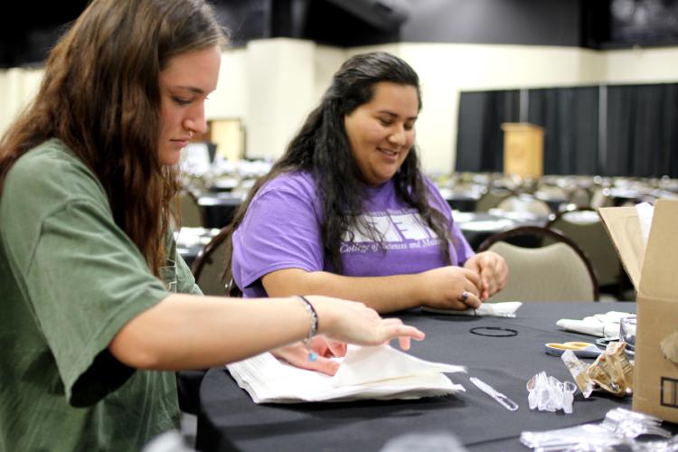 SFA interior design senior Calli Blankenship of Livingston and hospitality administration senior Yessenia Ramirez of Houston help prepare silverware for the annual Chairished Blessings fundraiser. 