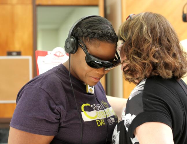 SFA senior interior design major Veronica Gilliams from Pensacola, Florida, strains to hear the five household chores Carolyn Johnson, a certified Dementia Live trainer for Heart to Heart Hospice, asks her to complete during the Dementia Live simulation.