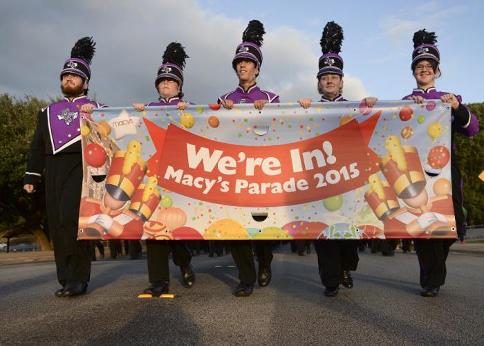 SFA's Lumberjack Marching Band members Harley Stahl, Katy Pleake, Vann Chandler, Sophia Lee and Shannon Valenta holding a banner announcing "We're In the Macys Thanksgiving Day Parade!" 