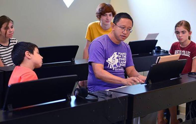 Dr. Mario Ajero, professor of piano at SFA, instructs a group of Music Prep piano students