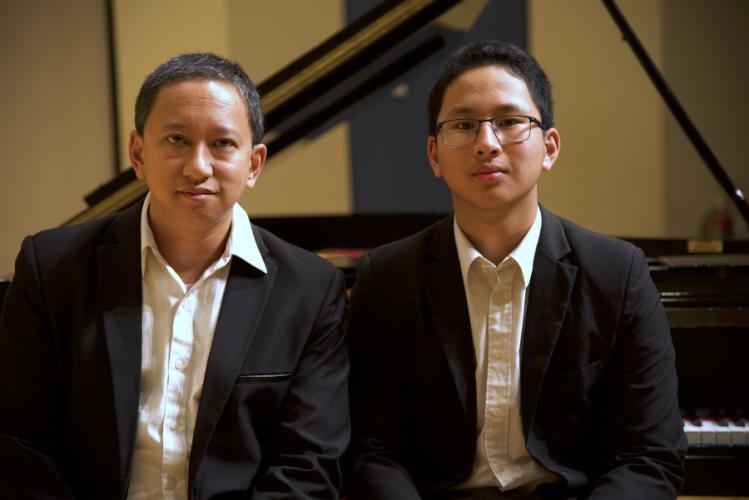 Mario Ajero and Nio Ajero sit next to each other on a piano bench.