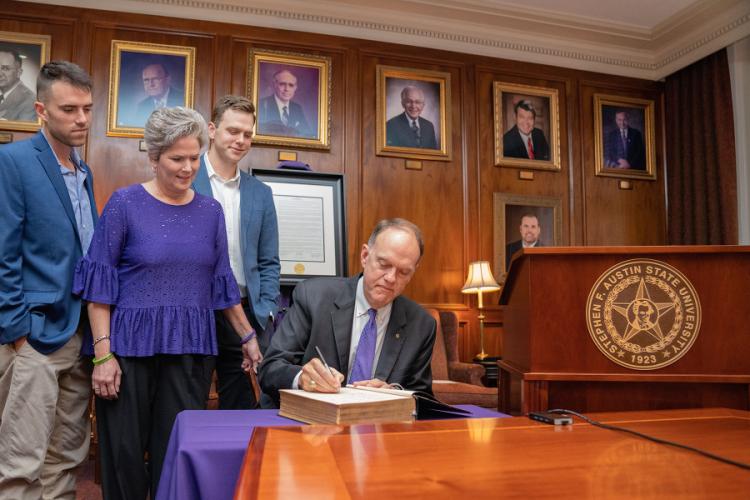 Westbrook signs the Bible all previous SFA presidents signed before him while surrounded by his family: wife, Dayna, and sons, Reed and Bryce.