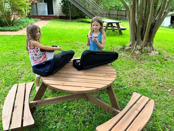 Two violinists use a donated table while getting ready to practice