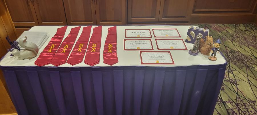 Graduation stoles and certificates presented to the five inductees are arranged on a table