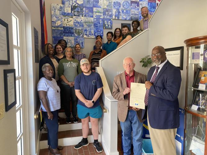 Nacogdoches County Commissioner Robin Dawley and Dr. Freddie Avant, director of the Stephen F. Austin State University School of Social Work, hold the proclamation while faculty members, field instructors, students and others in attendance stand behind on the School of Social Work Building’s grand staircase.