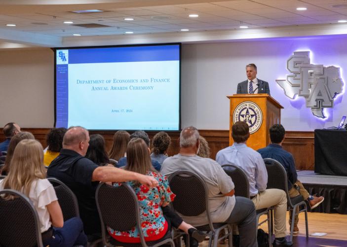 Dr. Mikhail Kouliavtsev, chair of Stephen F. Austin State University’s Department of Economics and Finance in the Rusche College of Business, presents students with monetary awards — many donated by Nacogdoches-area financial institutions — during an April 17 ceremony.