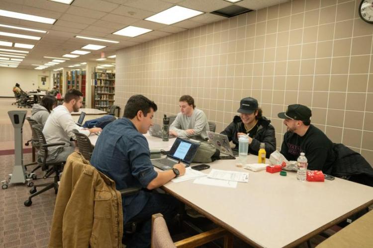 Students studying together at a large table in a library