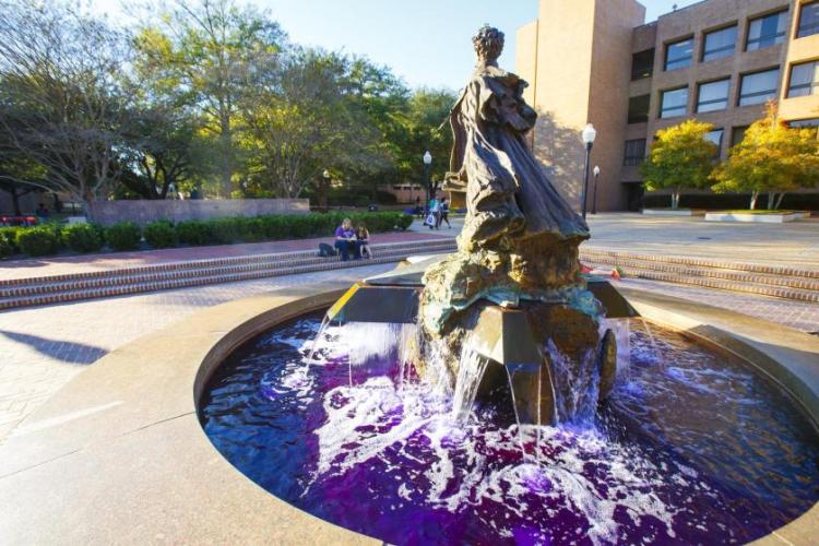 Stephen F. Austin statue and fountain with purple water in the campus courtyard