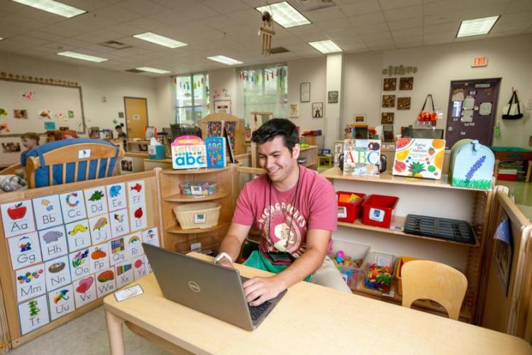 Student using a laptop in a colorful classroom with educational posters