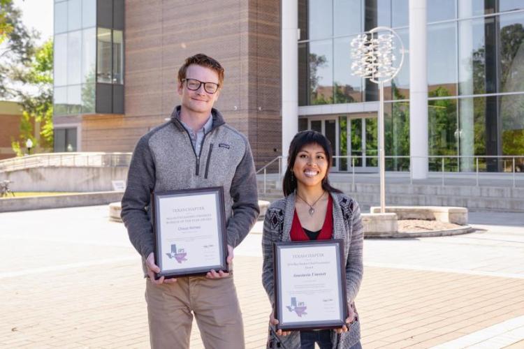 Two students holding certificates and smiling in front of one of SFA's modern facilities