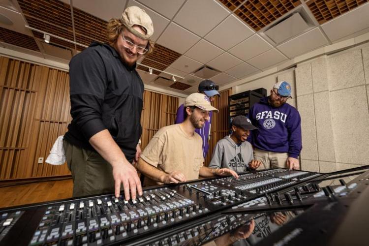 SFA students adjusting audio equipment in a recording studio