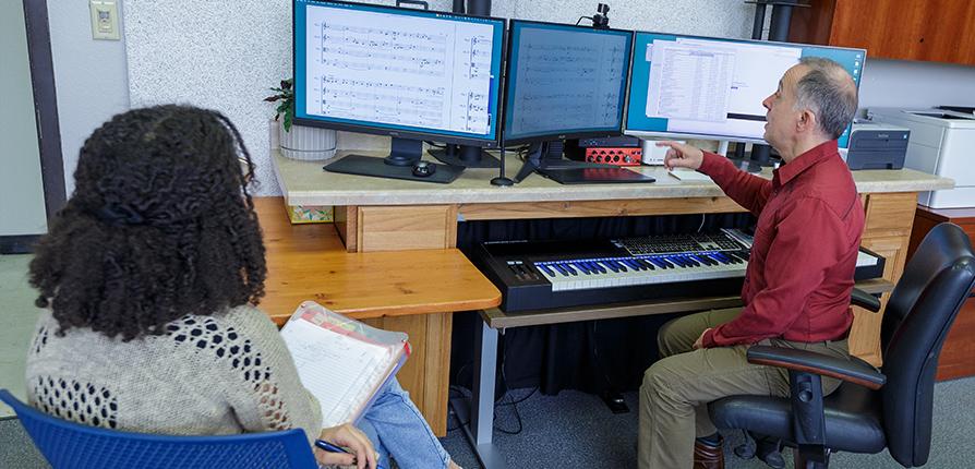 Faculty member meeting with student at a computer