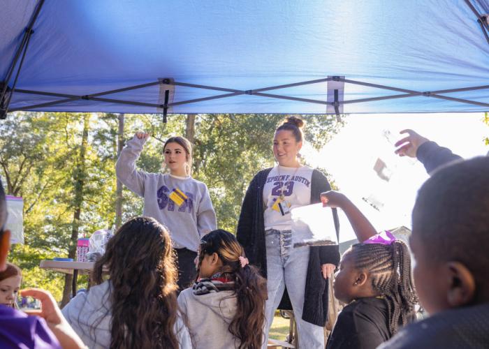 Two SFA preservice student teachers lead an outside science session with fourth and fifth grade students