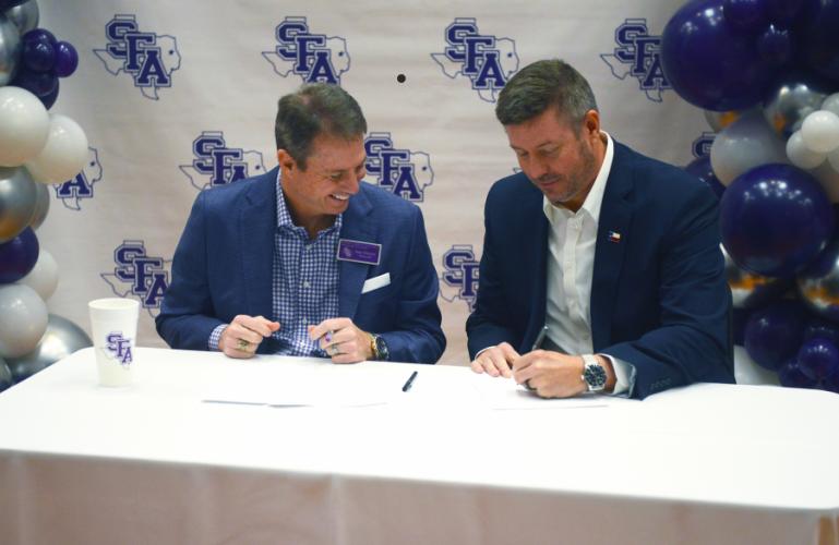 Dr. Neal Weaver, Stephen F. Austin State University president, looks on as Dr. Michael Simon, Angelina College president, signs the agreement making AC the first member of the Lumberjack Transfer Alliance recently.