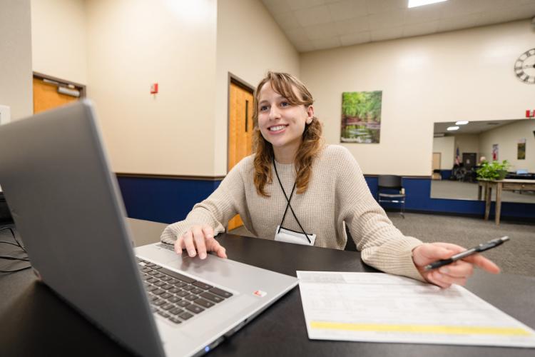 Senior accounting major Emily Pearson prepares taxes at a desk using a laptop and printed forms