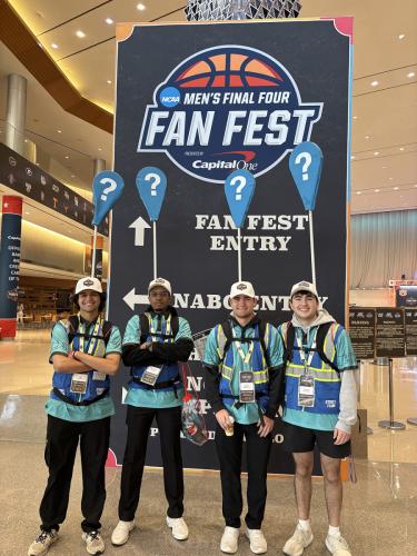 SFA sports business and media and communication student volunteers pose in front of a Final Four backdrop
