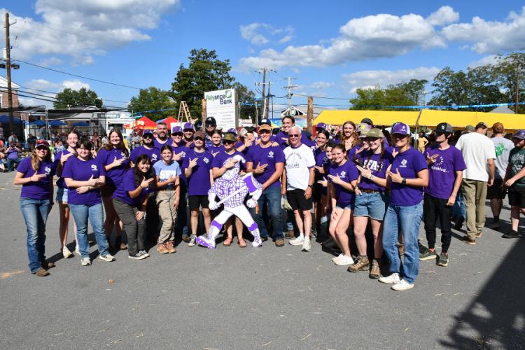 Members of the SFA Sylvans wearing purple and white stand together showing the SFA axe 'em hand sign