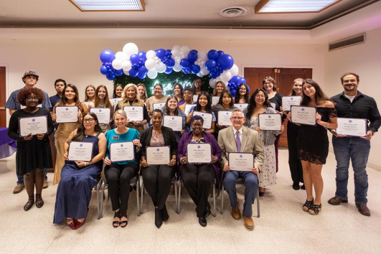 Members of Tri-Alpha holding certificates pose for a group photo