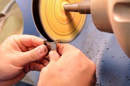 To finish a jewelry piece, Burgess uses the buffing machine, which often is used during the knife-making process.