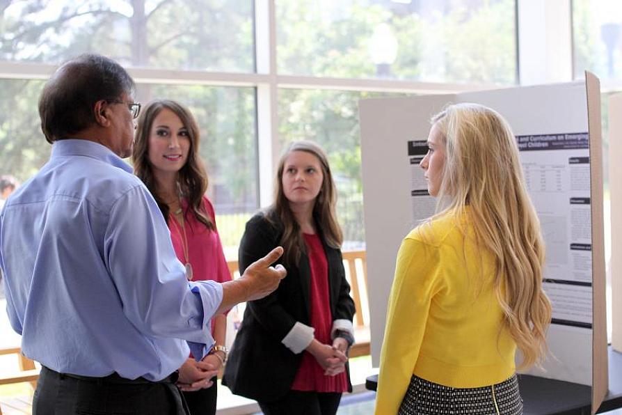 Dr. Nagalapura Viswanath visits with SLP graduate students about their research presentation.