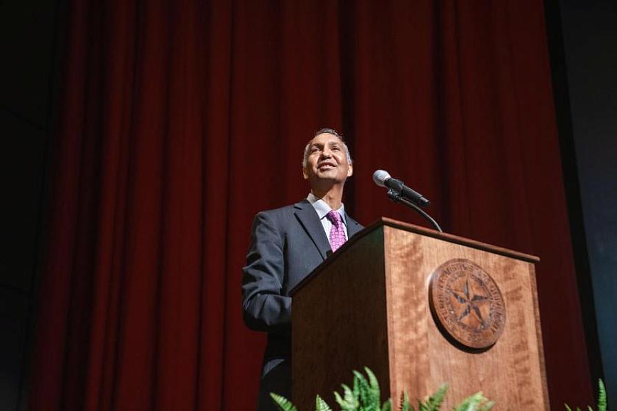 Speaker at a podium in front of a red curtain