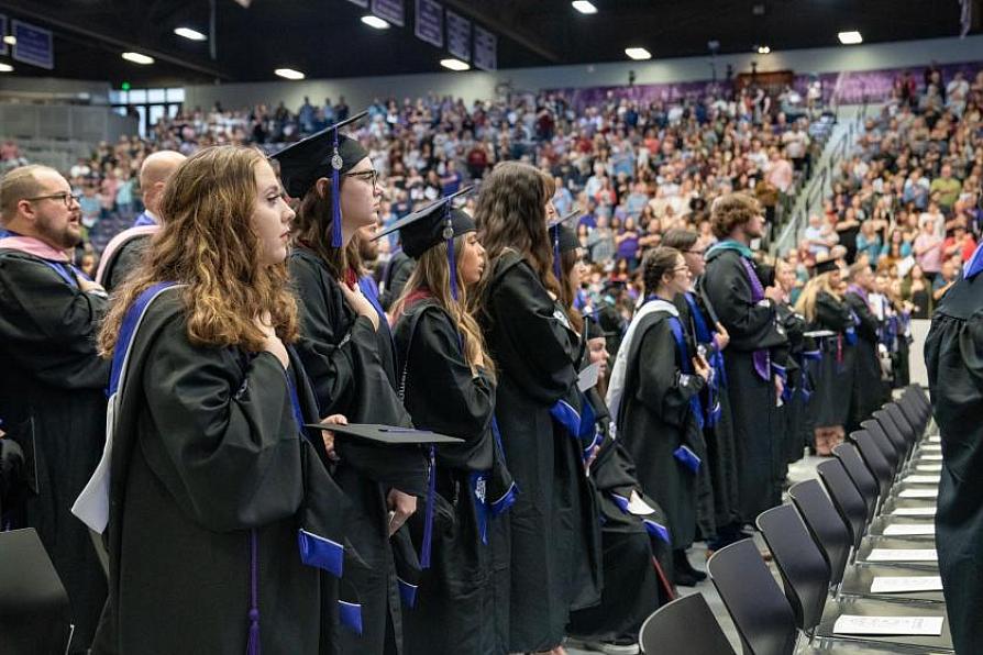 Graduates in caps and gowns standing during a commencement ceremony