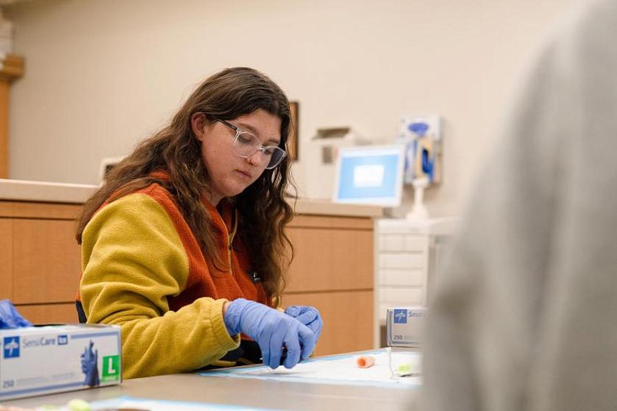 Student wearing gloves and concentrating on a lab task