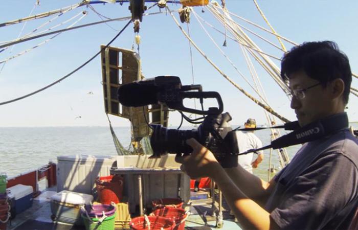 Filmmaker Tim Tsai on the deck of a boat in the filming of "Seadrift"