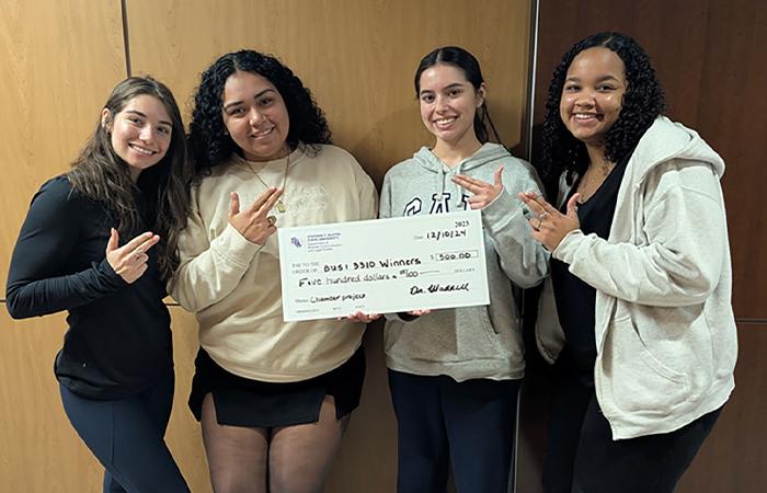 Four business students posing with check